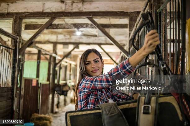 una foto de una joven de pie con caballos en un establo. una joven vaquera. - cowgirl hairstyles fotografías e imágenes de stock