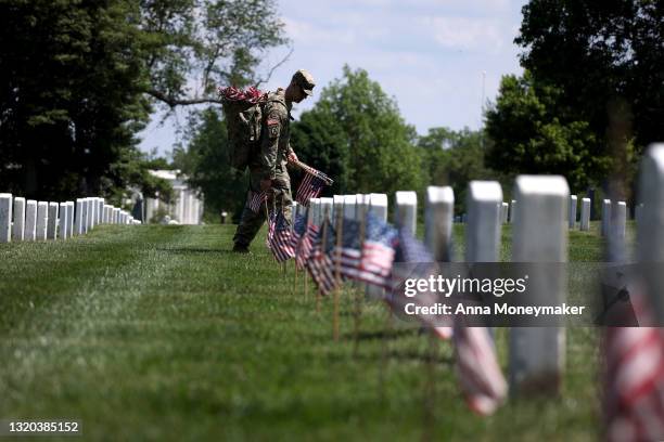 Service members place a small American flag in front of a grave site as part of the “Flags In” ceremony ahead of the Memorial Day weekend at...