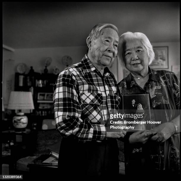 Portrait of an unidentified couple as they poses, holding their wedding portrait, in their apartment, Oakland, California, 1997.