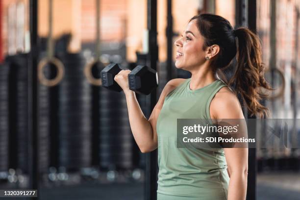 profilansicht leistungsstarke mitte erwachsene frau gewichtheben im fitnessstudio - working out at gym images stock-fotos und bilder