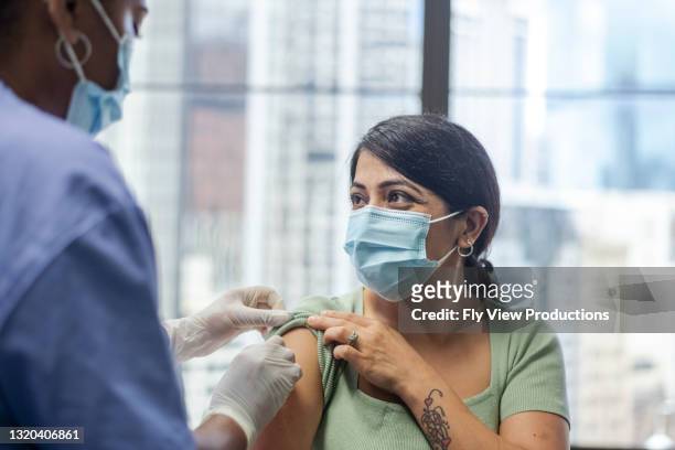 middle age woman receives covid-19 vaccine - aussie flu stock pictures, royalty-free photos & images