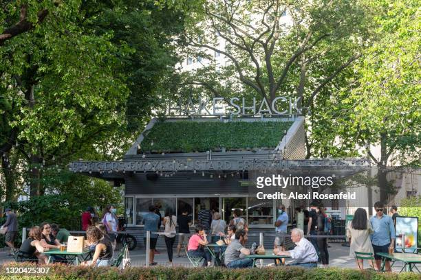 People sit outside Shake Shack in Madison Square Park on May 27, 2021 in New York City. On May 19, 2021 all pandemic restrictions, including mask...