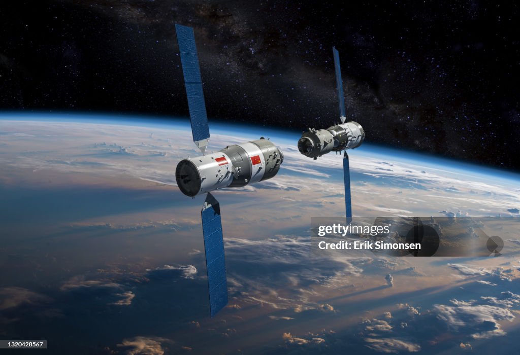 China's (PRC) Tiangong Space Station (foreground), as the Shenzhou spacecraft with Chinese taikonauts aboard approaches for docking in orbit above Earth.