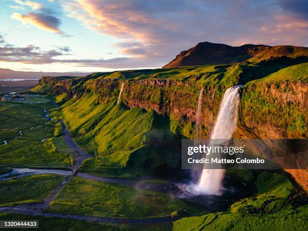 aerial of seljalandsfoss waterfall at sunset, iceland - sole di mezzanotte foto e immagini stock