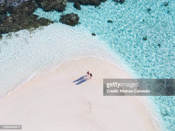 drone view of adult couple on a beach, maldives - travel couple stockfoto's en -beelden