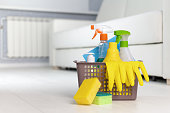 Cleaning service. Bucket with sponges, chemicals bottles on the background of the room.