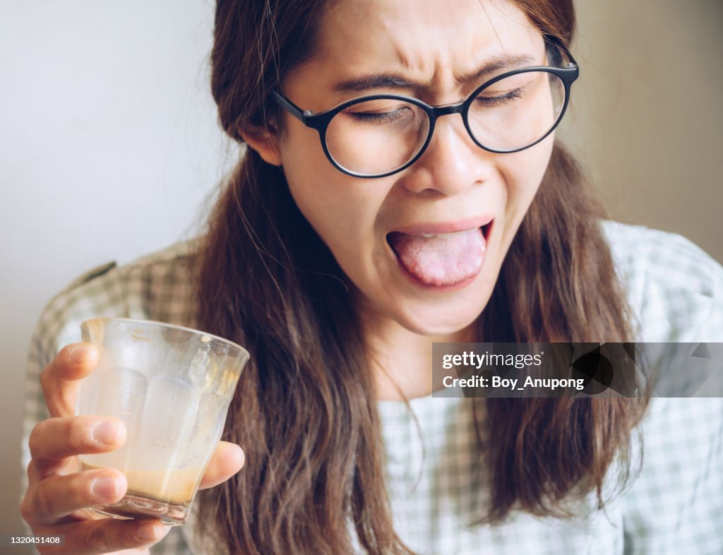 Facial expression of young Asian woman after drinking strong coffee.