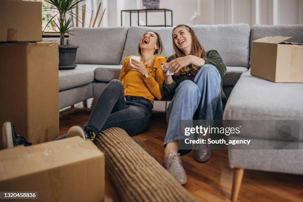 lesbian couple relaxing in new home - gay couple new house stock pictures, royalty-free photos & images