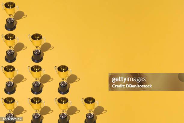 winner gold cups trophy pattern with hard shadow on yellow background on the left side, with copy space on the right. winner victory concept - antonio valencia wins carling goal of the month award stockfoto's en -beelden