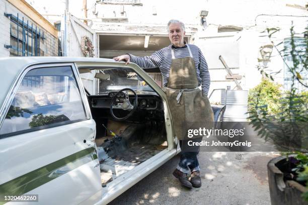 hogere autorestaurateur die op klassiek werk in uitvoering leunt - classic car restoration stockfoto's en -beelden