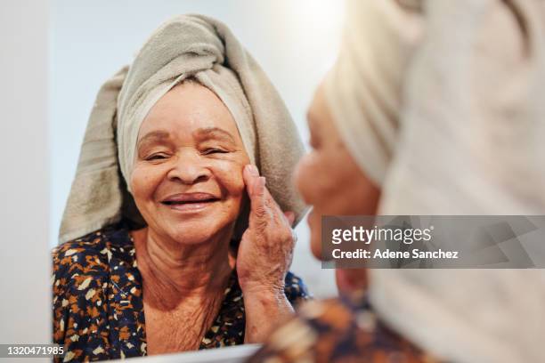 shot of a mature woman applying her skincare in the bathroom - aged to perfection stock pictures, royalty-free photos & images