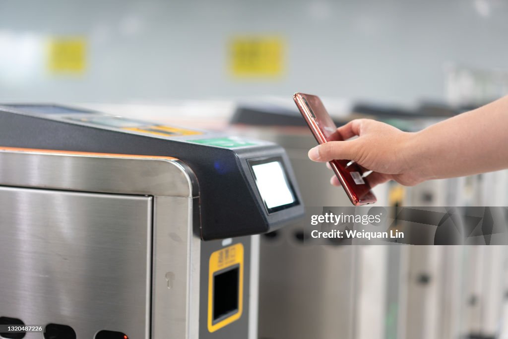 People who are using a smartphone QR code to scan into a subway station