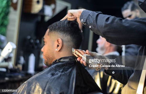 young man having a haircut at a barbershop - barbers stock pictures, royalty-free photos & images