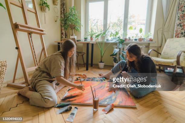 two women painting on the floor at their apartment - house for an art lover stock pictures, royalty-free photos & images