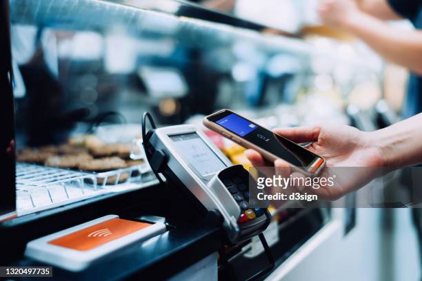 close up of a woman's hand paying with her smartphone in a cafe, scan and pay a bill on a card machine making a quick and easy contactless payment. nfc technology, tap and go concept - paying stock-fotos und bilder