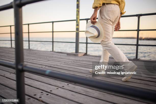 mann trägt hosen und espadrilles zu fuß auf holzdock auf dem meer - beige pants stock-fotos und bilder