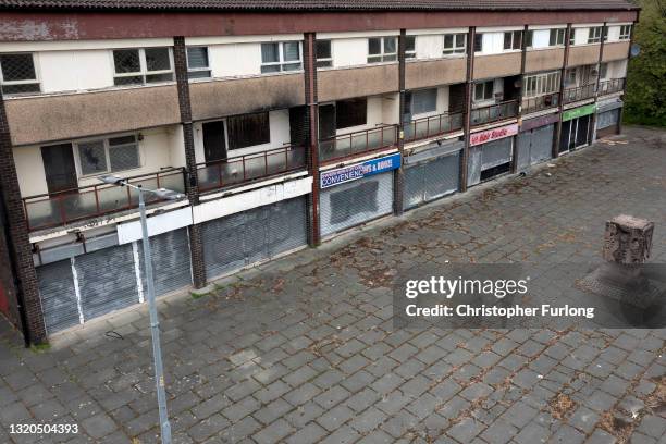 Broken windows and shuttered shops blight the landscape in Collyhurst on May 28, 2021 in Manchester, England. A row of derelict shops and homes in...