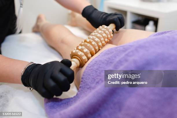 wood therapy massage with a wooden roller on the legs inside a clinic - sistema linfatico foto e immagini stock