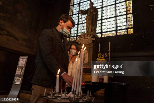 Laurent Frémont, an activist calling for a legal right for people to visit hospital patients, lights a candle at a service in memory of those who...