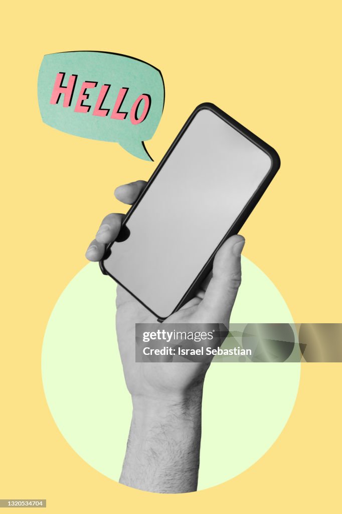 Hand holding a smartphone on yellow background while a sign appears with "HELLO" words.