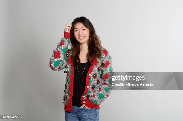 portrait of a asian millennial woman with long hair, wearing an red and green patterned ugly sweater with a black tank and blue jeans. - ugly black women ストックフォトと画像