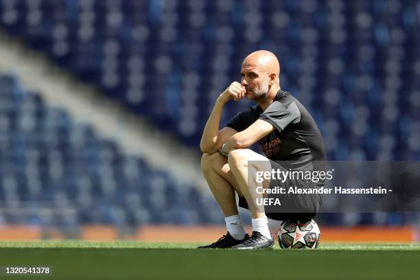 Pep Guardiola, Manager of Manchester City sits on a ball as he looks on during the Manchester City FC Training Session ahead of the UEFA Champions...