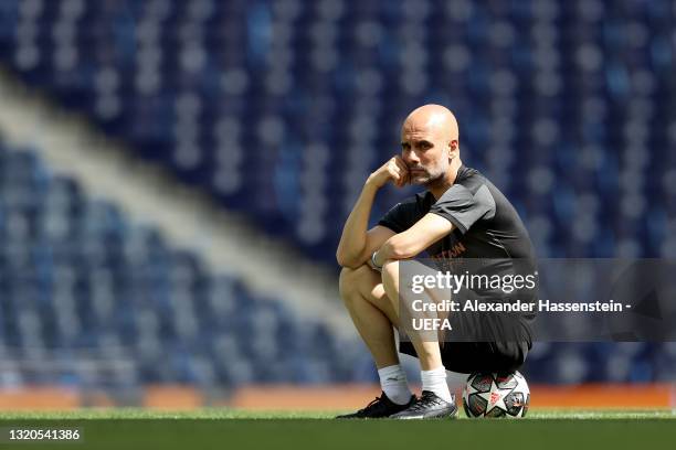 Pep Guardiola, Manager of Manchester City sits on a ball as he looks on during the Manchester City FC Training Session ahead of the UEFA Champions...