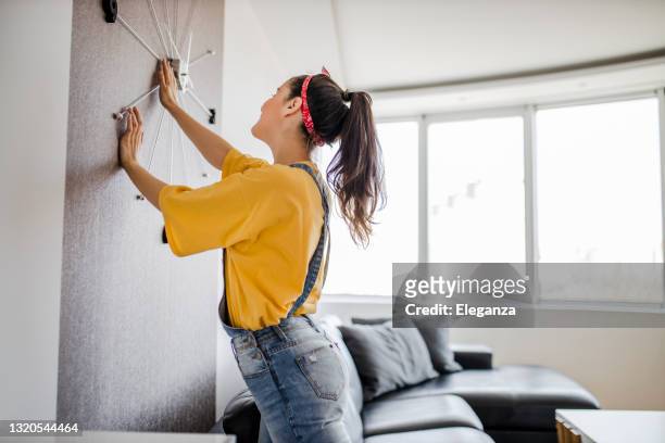 young woman decorating her home - wall clock stock pictures, royalty-free photos & images