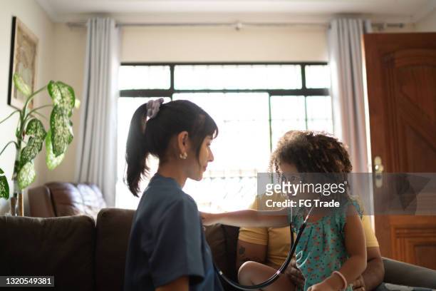 kind spielt bei hausbesuch mit dem stethoskop der krankenschwester - pediatric nurse stock-fotos und bilder
