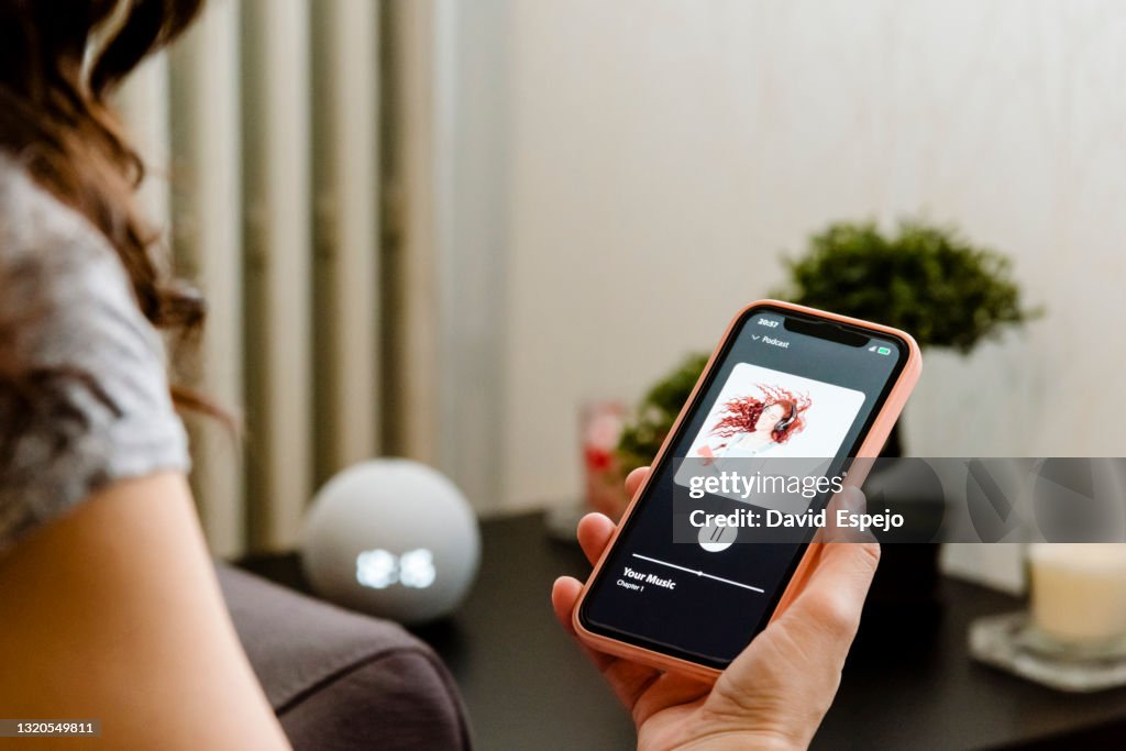Woman choosing music on her cell phone to listen to on her smart speaker