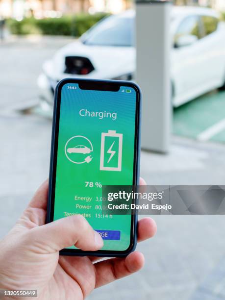 close-up shot of a man looking at his electric car charging app - electric car home stock pictures, royalty-free photos & images