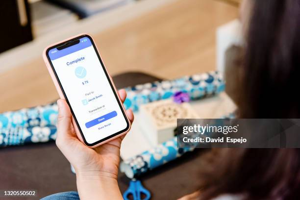 woman sending money to a friend through a mobile phone - shopping screen stock-fotos und bilder