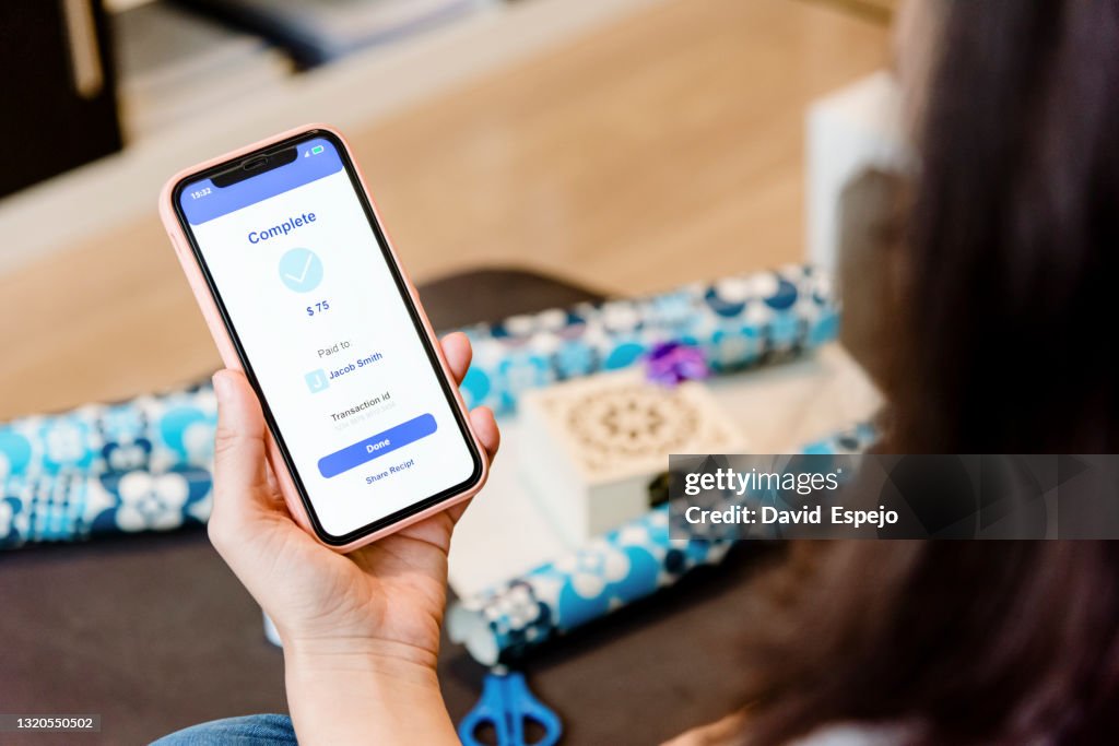 Woman sending money to a friend through a mobile phone