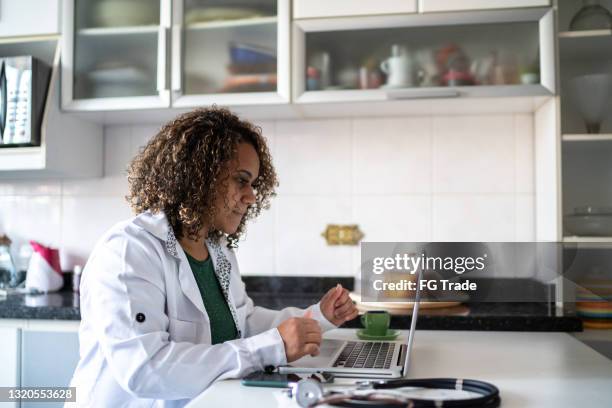 doctor working or doing a telemedicine call using laptop at home - virtual visit stock pictures, royalty-free photos & images
