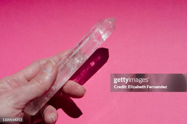 woman's hand holding quartz crystal on pink background - healing crystals stock pictures, royalty-free photos & images