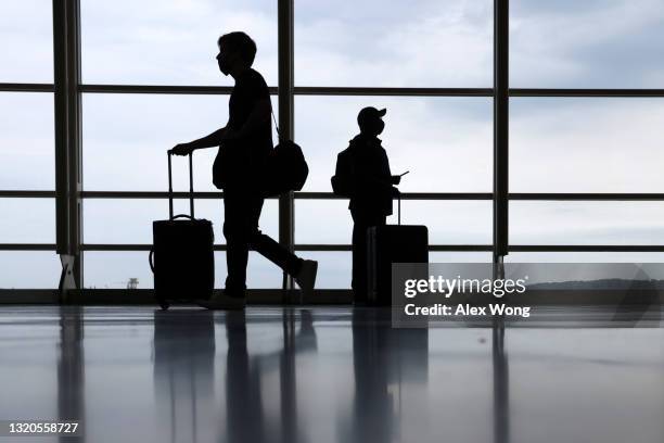 Travelers pass through the concourse at Ronald Reagan Washington National Airport on the eve of Memorial Day long weekend May 28, 2021 in Arlington,...