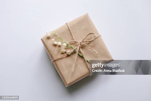 gift box wrapped with craft brown paper and spring lily-of-the-valley white flowers, vintage style card. - anna kraft stock pictures, royalty-free photos & images