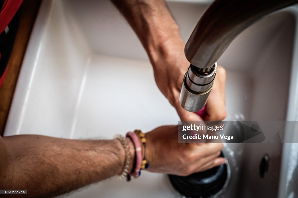 Top view of a plumber using a pipe plunger to fix kitchen sinks