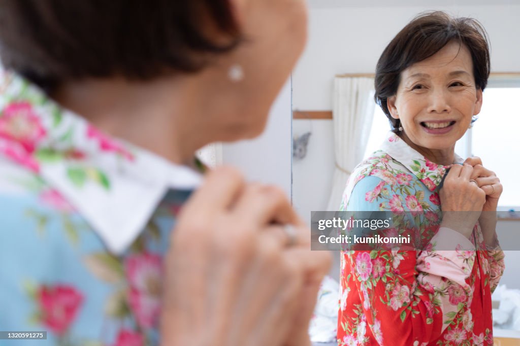 Senior women enjoying online shopping, fitting clothes at home