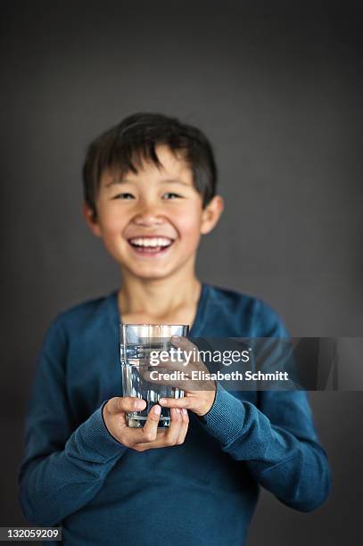 laughing boy with glass of water in his hand - glass of water hand ストックフォトと画像