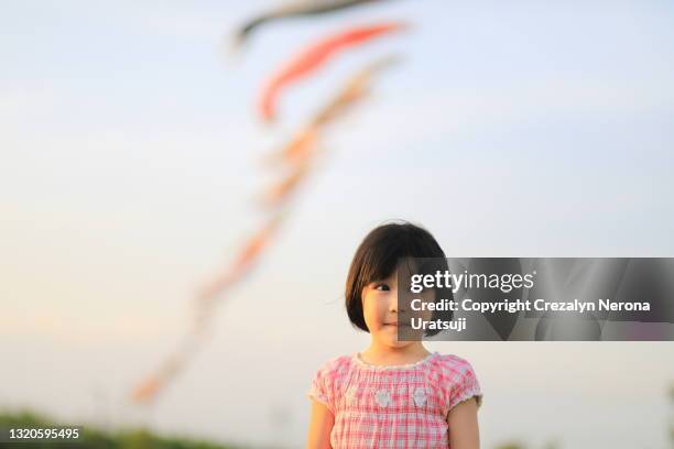 cute little girl with carp streamer on background  looking away - koinobori stock pictures, royalty-free photos & images