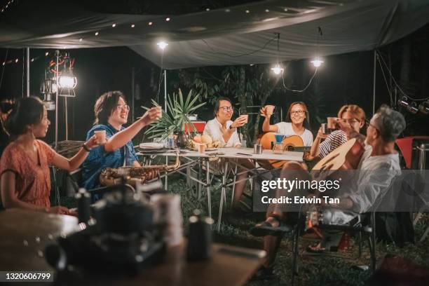 asian chinese family and friends enjoy coffee drinks at garden party gathering camping tent at night - asian family camping stock pictures, royalty-free photos & images