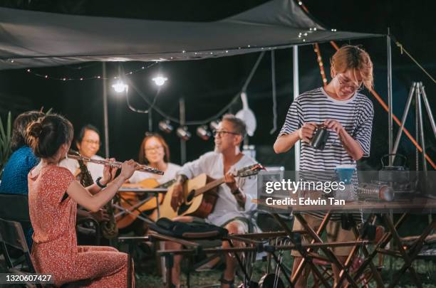 asian chinese teenage boy pouring hot water making brewing drip coffee while friends enjoy playing music instrument garden party gathering camping tent at night - hot sax stock pictures, royalty-free photos & images
