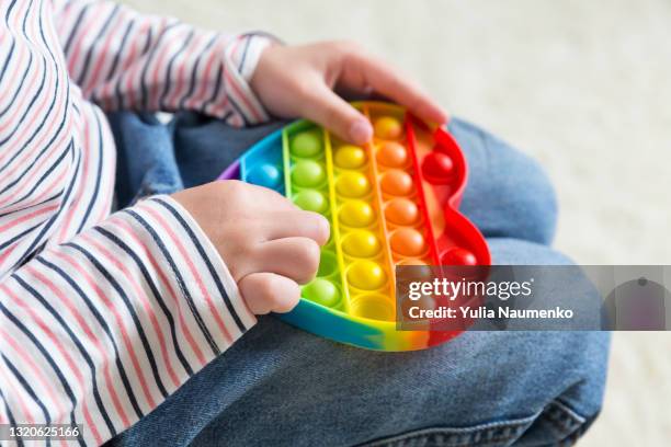 child playing with antistress toy - rainbow kids stock-fotos und bilder