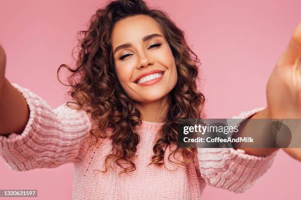 photography of a cheerful girl making selfie over pink background - wavy hair model stock pictures, royalty-free photos & images
