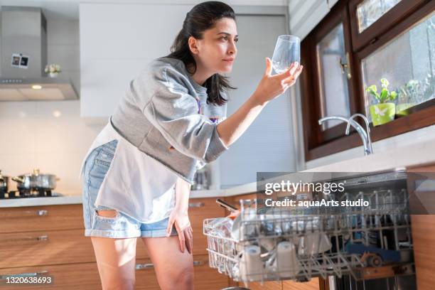 de jonge vrouw neemt een glas uit de afwasmachine in keuken. - wasserglas stockfoto's en -beelden