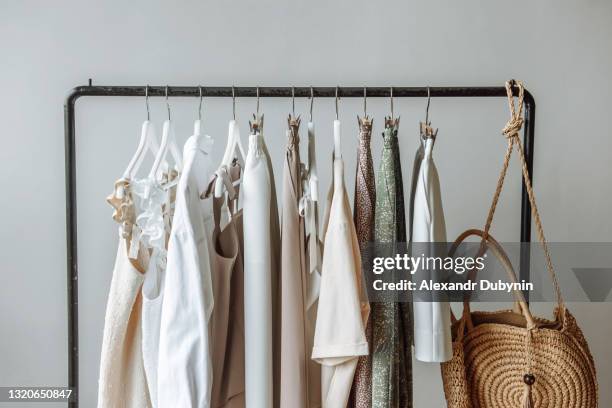 close-up of a wardrobe of clothes hanging on a rail against a white background in a studio store - vestuario fotografías e imágenes de stock