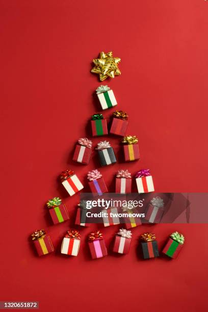 conceptual christmas tree form by gift boxes on red background. - flat lay stock-fotos und bilder