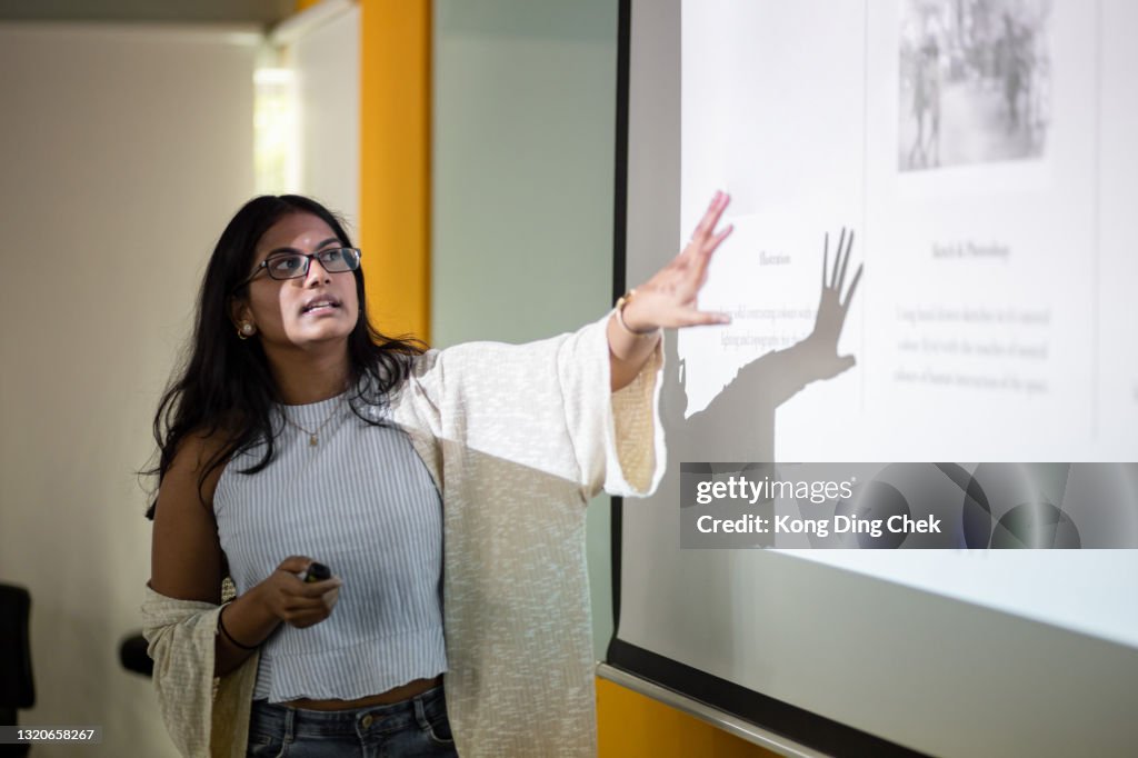 Asian college student is making a presentation in front of projector screen