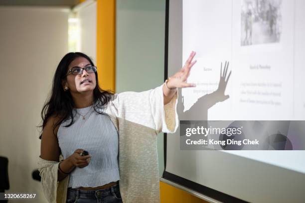 estudante universitário asiático está fazendo uma apresentação em frente à tela do projetor - sala de conferência - fotografias e filmes do acervo